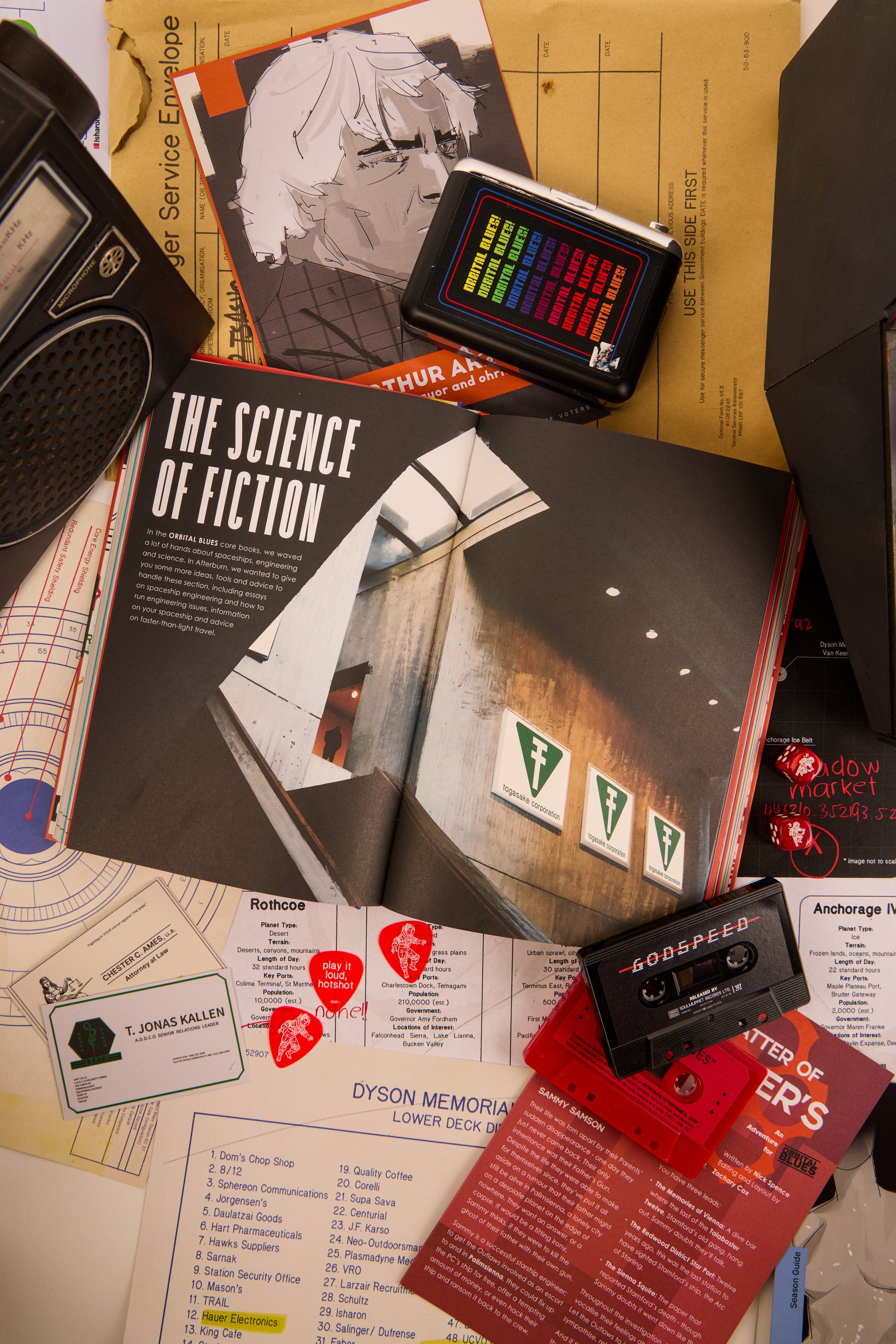 Double page spread of "The Science of Fiction" from Afterburn surrounded by cassettes and other various items